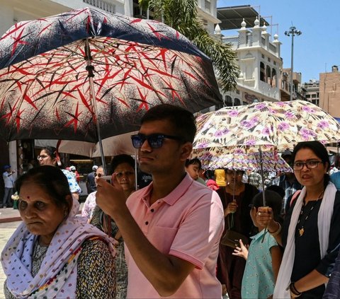 Mereka terpaksa harus menggunakan payung maupun penutup wajah untuk menghindari sinar teruk matahari yang menyengat. Foto: AFP<br>