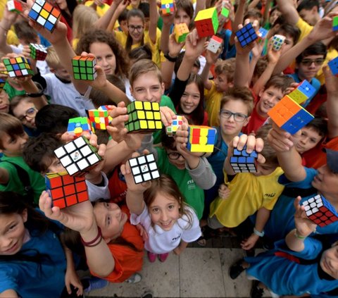 Acara ini diwarnai dengan flashmob spektakuler yang melibatkan ratusan murid dari berbagai sekolah di seluruh negeri. Mereka masing-masing memegang Kubus Rubik berwarna-warni. Foto: Ferenc ISZA / AFP<br>