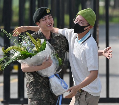 Personel boyband K-Pop BTS, Jin mendapat pelukan hangat dari rekannya J-Hope saat keluar dari pangkalan militer di Yeoncheon, Korea Selatan, pada 12 Juni 2024. Jin akhirnya mendapatkan bebas tugas dinas militer setelah menyelesaikan wajib militer (wamil). Foto: Jung Yeon-Je/AFP