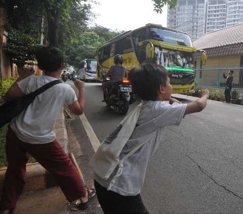 Sejumlah anak berjoget ketika mendengarkan klakson telolet atau klakson tidak standar, yang biasanya mengeluarkan nada-nada tak biasa, dari sebuah bus yang meninggalkan kawasan Taman Margasatwa Ragunan, Jakarta, Kamis (13/6/2024). Meski mengancam nyawa, nyatanya masih banyak anak-anak yang tetap nekat berburu klakson telolet dari bus-bus yang melintas. Foto: Merdeka.com/Imam Buhori