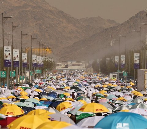 Sejumlah jemaah haji memakai payung saat berjalan menuju Jabal Rahmah untuk menunaikan wukuf di Padang Arafah, Makkah, Arab Saudi, pada Sabtu (15/6/2024). Seluruh jemaah haji dari berbagai dunia berkumpul di Padang Arafah untuk melaksanakan wukuf. Foto: Fadel Senna/AFP