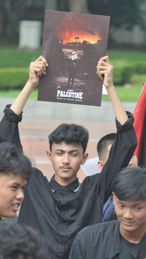 Seorang pengunjuk rasa mengangkat poster saat menggelar aksi solidaritas untuk Palestina di Tugu Proklamasi, Jakarta, Sabtu (15/6/2024). Merdeka.com/Imam Buhori