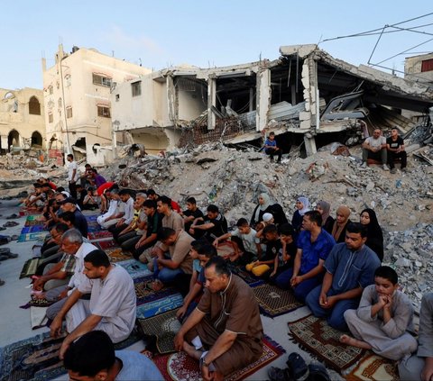 Warga Palestina di Khan Younis, Gaza pada hari Minggu (16/6/2024) mengadakan salat Iduladha di tengah reruntuhan Masjid Al-Rahma dan bangunan lainnya yang telah dihancurkan oleh serangan udara Israel. Foto: REUTERS / Mohammed Salem<br>