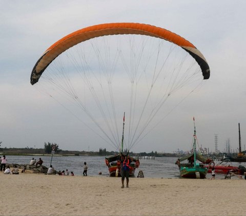 Selain berwisata dengan perahu di Pantai Ancol, pengunjung juga dapat menikmati serunya terbang bak paralayang  dengan parasut yang ditarik speedboat. Foto: Liputan6.com / Herman Zakharia