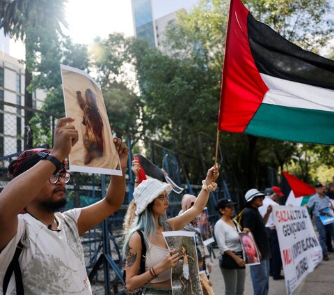 Pengunjuk rasa terlihat mengibarkan bendera Palestina saat mengecam serangan militer Israel di kota Rafah, Gaza. <br><br>Pada Jumat (31/5/2024) lalu, militer zionis Israel melancarkan serangan brutal di sejumlah wilayah Kota Gaza yang sudah ditargetkan. Foto: Reuters