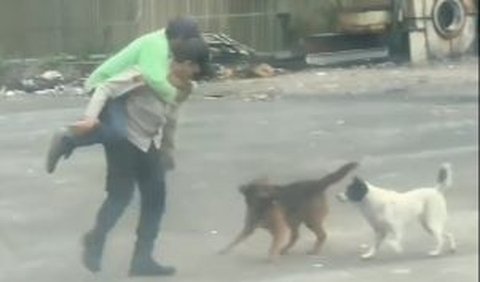 Terlihat dalam video, bapak satpam ini bahkan sampai dikelilingi oleh dua ekor anjing. <br>