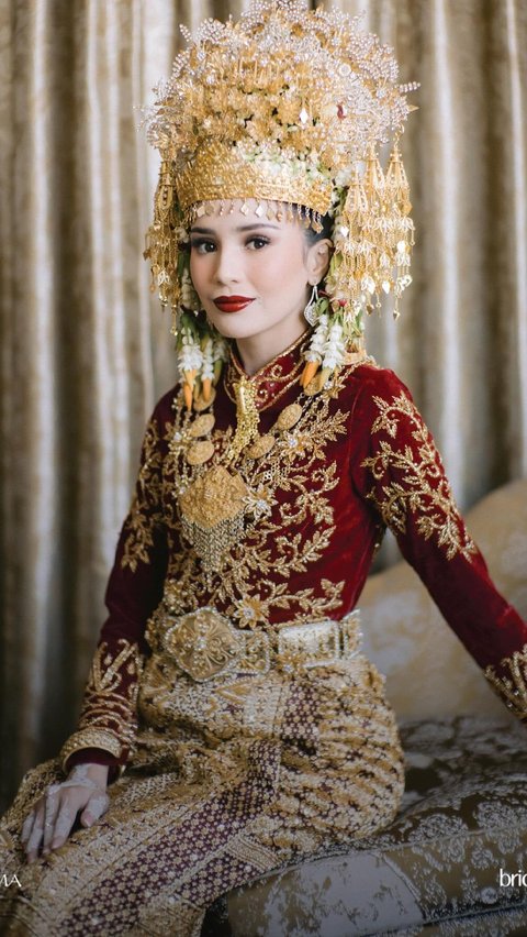 Beby looks charming in a red traditional Acehnese attire with a glowing gold accent.
