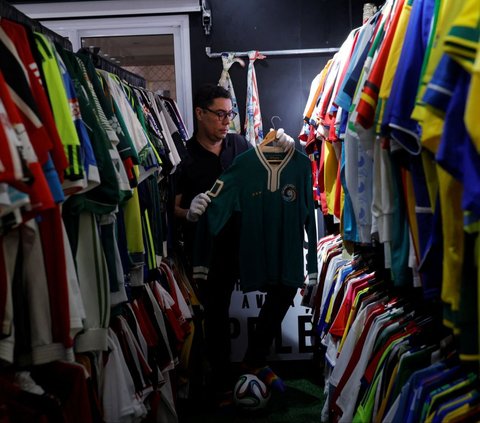 Cassio Brandao asal Brasil menunjukkan salah satu koleksinya pada sebuah ruangan dengan rak-rak yang dipenuhi jersey sepak bola di Sao Paulo, Brasil, pada 24 Juni 2024. Pada April 2024 lalu, Brandao memecahkan rekor dunia Guinness World Records sebagai pemilik koleksi kaos sepak bola terbanyak di dunia. Foto: REUTERS/Amanda Perobelli