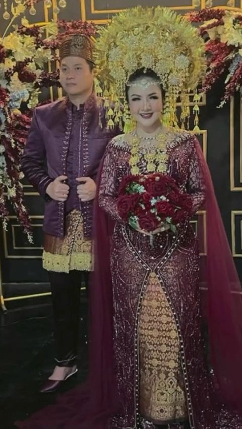 Ia is wearing traditional Minang clothes in red, complete with a golden suntiang, making it look luxurious and elegant.