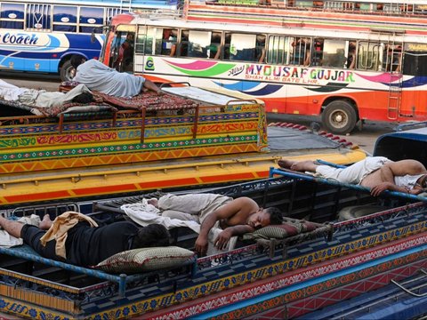 FOTO: Di Tengah Gelombang Suhu Panas Ekstrem, Sopir Bus di Pakistan Ini Justru Tidur Nyenyak di Luar Ruangan