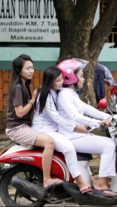 Tiga orang menaiki sepeda motor