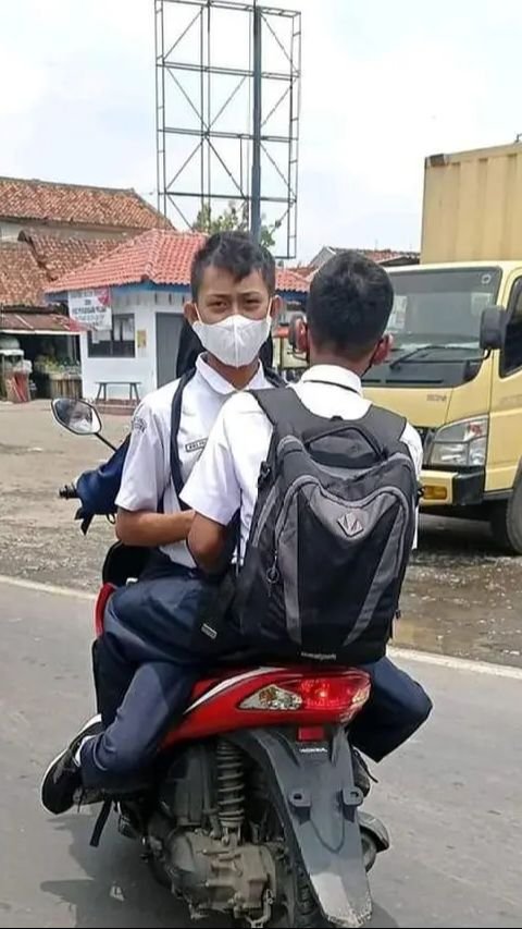 Tiga orang menaiki sepeda motor