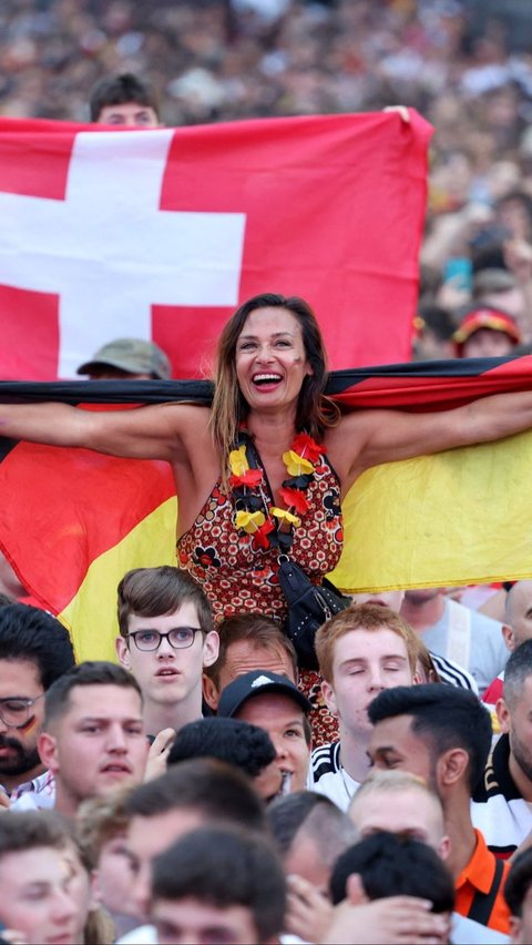 Suporter cantik Jerman membentangkan bendera saat mendukung langsung Tim Panser. Foto: AFP