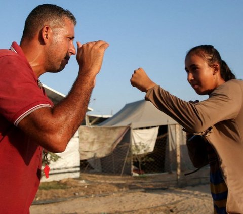 Di tempat yang penuh dengan kesedihan, pelatih tinju Palestina, Osama Ayoub, berdedikasi untuk memberikan semangat dan harapan kepada para gadis muda Palestina melalui olahraga tinju. Foto: REUTERS / Hatem Khaled<br>