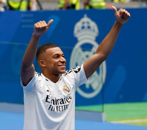 Bintang sepakbola Prancis, Kylian Mbappe tersenyum menyapa para suporter ketika diperkenalkan sebagai pemain baru Real Madrid di Stadion Santiago Bernabeu, Madrid, Spanyol, Selasa (16/7/2024). Mbappe resmi bergabung tim raksasa Spanyol setelah meninggalkan PSG dengan status bebas transfer. Foto: REUTERS/Juan Medina