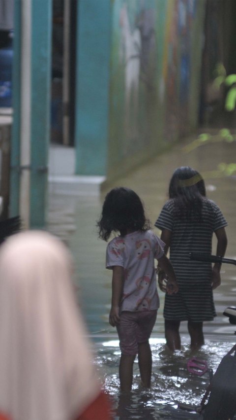 Sejumlah anak bermain ketika banjir akibat luapan Kali Ciliwung merendam permukiman di Kebon Pala, Jatinegara, Jakarta, Selasa (2/7/2024). Merdeka.com/Imam Buhori