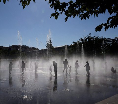 Sejumlah warga mandi di bawah guyuran air mancur di Taman Madrid Rio, Madrid, Spanyol, pada 23 Juli 2024. Spanyol dilanda gelombang panas dengan suhu diperkirakan bisa melampaui 40 derajat celcius selama musim panas tahun ini. Foto: Oscar Del Pozo/AFP