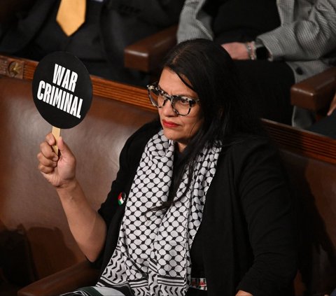 Anggota DPR Amerika Serikat (AS) dari Partai Demokrat, Rashida Tlaib mengangkat plakat 'Penjahat Perang' saat Perdana Menteri (PM) Israel Benjamin Netanyahu berpidato pada Kongres Amerika Serikat (AS) di Capitol Hill, Washington, AS, pada Rabu (24/7/2024). Tlaib memberikan respons berbeda dari kebanyakan hadirin Kongres AS ketika mendengar pidato Netanyahu. Foto: AFP