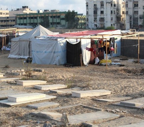 Sejumlah tenda pengungsian berdiri di sebuah kuburan di Khan Younis, Jalur Gaza, Palestina, pada Jumat (26/7/2024). Sekelompok warga Palestina yang telah kehilangan tempat aman akibat serangan udara Israel terpaksa mengungsi di sebuah kuburan.  Foto: Bashar Taleb/AFP