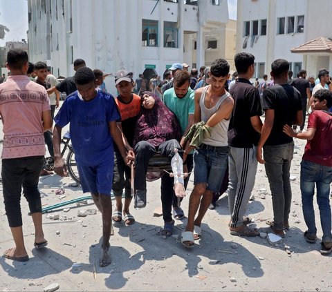 Seorang wanita Palestina yang terluka dibawa ke ambulans setelah serangan udara Israel menghantam sekolah Khadija di Deir al-Balah, Jalur Gaza, Palestina, pada 27 Juli 2024. Israel lagi-lagi menargetkan sekolah yang jadikan kamp pengungsian dalam serangan terbarunya di Jalur Gaza. Foto: Eyad Baba/AFP