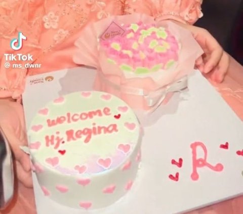 Saat masih di perjalanan, wanita bernama Regina ini sudah mendapat kue untuk menyambutnya yang bertuliskan 'Welcome Hj. Regina'. Tak hanya satu, ia mendapatkan dua kue sekaligus.