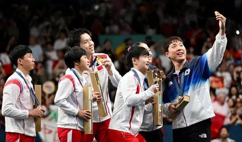 Peraih medali perunggu Lim Jonghoon dari Korea Selatan (kanan) berselfie di atas podium bersama rekan setimnya Shin Yubin, peraih medali emas Wang Chuqin dan Sun Yingsha dari China serta peraih medali perak Ri Jong Sik dan Kim Kum Yong dari Korea Utara pada Olimpiade Paris 2024 di South Paris Arena, Selasa (30/7/2024).