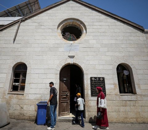 Warga Palestina berdiri di luar Gereja Baptis yang rusak akibat serangan militer Israel dan diubah menjadi klinik di Kota Gaza, Jalur Gaza, pada 1 Juli 2024. Setelah agresi militer Israel menghancurkan sistem kesehatan di Jalur Gaza, pendeta Gereja Baptis pun berinisiatif mengubah rumah ibadahnya menjadi klinik untuk merawat korban perang. (REUTERS/Dawoud Abu Alkas)