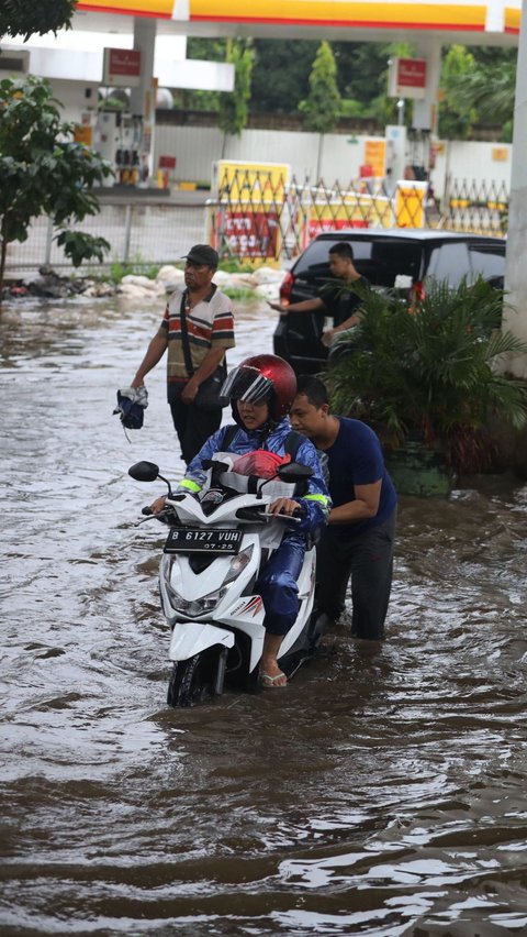 Seorang warga membantu pengendara melewati banjir yang merendam Jalan Ciledug Raya, Jakarta Selatan, Sabtu (6/7/2024).  Liputan6.com/Angga Yuniar