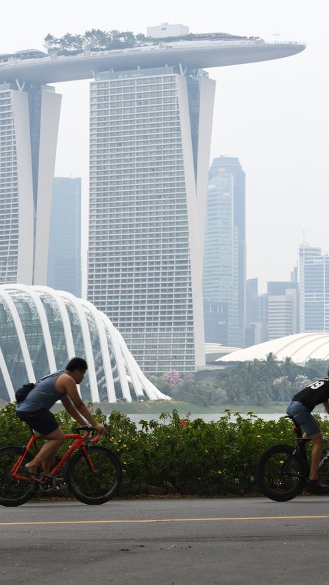 Warga beraktivitas saat kabut asap menyelimuti kota Singapura (15/9/2019). Akibat kabut asap yang terjadi di kota tersebut membuat Grand Prix Formula 1 di Singapura pekan depan, 20-22 September 2019, terancam batal.  (AFP Photo/Roslan Rahman)