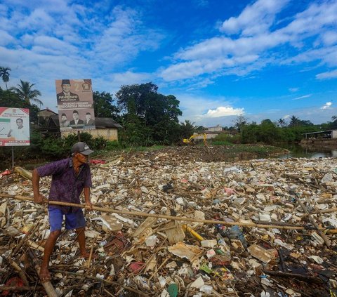 Warga memilah sampah yang dapat didaur ulang pada tumpukan sampah yang dibawa aliran Sungai Pesanggrahan di Jembatan Kampung Bulak barat-Pasir Putih, Depok, Jawa Barat, Minggu (07/07/2024).  Sampah rumah tangga yang dibawa aliran Kali Pesanggrahan sejak kemarin disebabkan kurangnya kesadaran warga untuk menjaga kebersihan sungai.