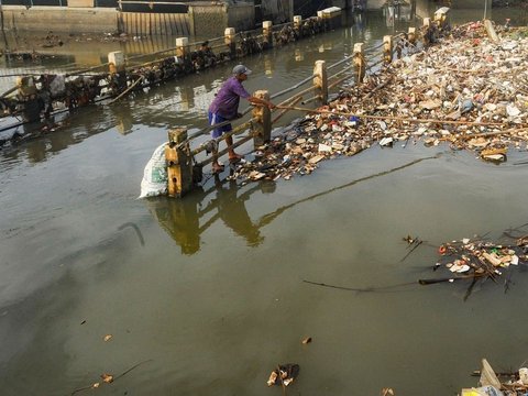 Warga memilah sampah yang dapat didaur ulang pada tumpukan sampah yang dibawa aliran Sungai Pesanggrahan di Jembatan Kampung Bulak barat-Pasir Putih, Depok, Jawa Barat, Minggu (07/07/2024).  Sampah rumah tangga yang dibawa aliran Kali Pesanggrahan sejak kemarin disebabkan kurangnya kesadaran warga untuk menjaga kebersihan sungai.