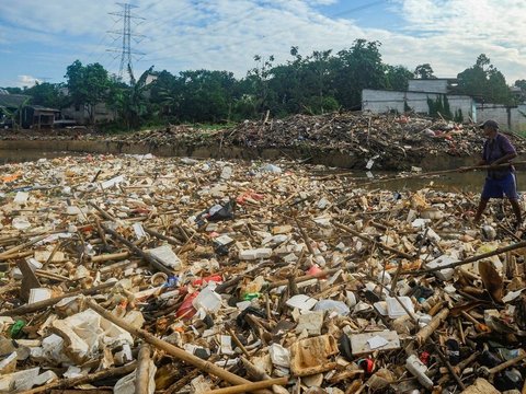 Warga memilah sampah yang dapat didaur ulang pada tumpukan sampah yang dibawa aliran Sungai Pesanggrahan di Jembatan Kampung Bulak barat-Pasir Putih, Depok, Jawa Barat, Minggu (07/07/2024).  Sampah rumah tangga yang dibawa aliran Kali Pesanggrahan sejak kemarin disebabkan kurangnya kesadaran warga untuk menjaga kebersihan sungai.