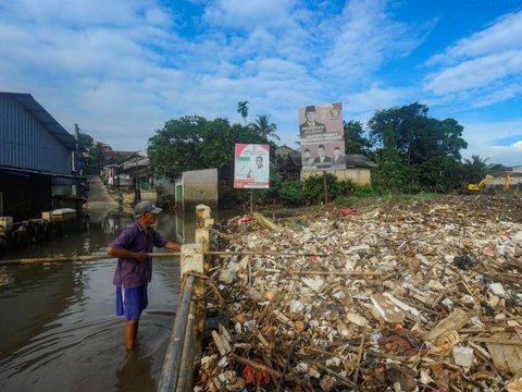 Warga memilah sampah yang dapat didaur ulang pada tumpukan sampah yang dibawa aliran Sungai Pesanggrahan di Jembatan Kampung Bulak barat-Pasir Putih, Depok, Jawa Barat, Minggu (07/07/2024).  Sampah rumah tangga yang dibawa aliran Kali Pesanggrahan sejak kemarin disebabkan kurangnya kesadaran warga untuk menjaga kebersihan sungai.