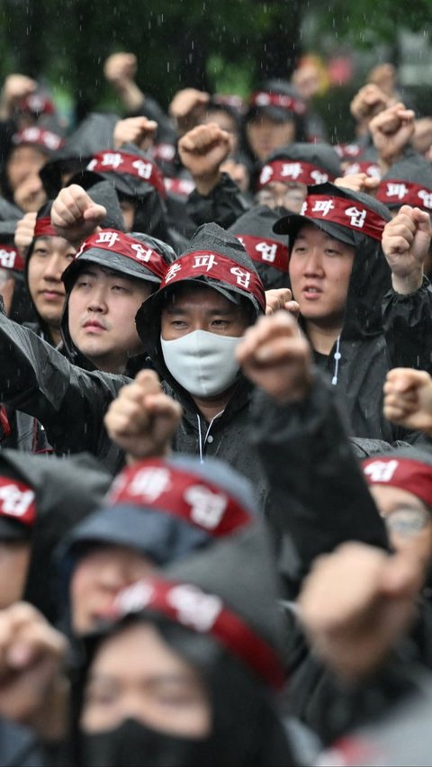 Dalam aksinya, ribuan buruh dengan mantel hitam dan ikat kepala merah berkumpul dan berbaris rapi di depan pabrik. Foto: Jung Yeon-je/AFP