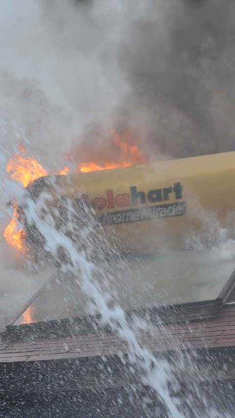 Terlihat kobaran api membakar atap bangunan rumah tersebut saat petugas pemadam kebakaran berjibaku melakukan penjinakan api. Foto: merdeka.com / Imam Buhori