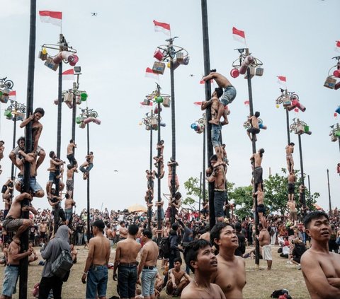 Di samping festival dan pawai budaya, berbagai ajang perlombaan juga diadakan untuk menambah semarak perayaan. Salah satunya lomba panjat pinang yang paling diminati oleh masyarakat. Foto: Yasuyoshi CHIBA / AFP