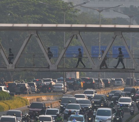 Sejumlah pekerja berjalan melewati Jembatan Penyeberangan Orang (JPO) di kawasan Jalan Sudirman, Jakarta, Selasa (27/8/2024). Badai pemutusan hubungan kerja (PHK) menghantam Indonesia. Berdasarkan data Kementerian Tenaga Kerja (Kemnaker), terdapat 32.064 orang yang terkena PHK dalam periode Januari-Juni 2024. Foto: Merdeka.com/Imam Buhori