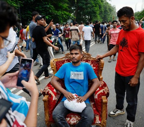 Seorang pengunjuk rasa duduk di sebuah sofa yang dijarah dari Ganabhaban, rumah Perdana Menteri Bangladesh, di Dhaka, Bangladesh, pada 5 Agustus 2024. Pengunjuk rasa menyerbu kediaman PM Bangladesh yang mewah dengan menjarah berbagai perabotan dan TV.  REUTERS/Mohammad Ponir Hossain