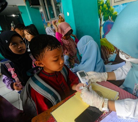 Petugas medis dari Puskesmas Ciputat melakukan tes gula darah pada seorang siswa di SDN 04 Ciputat, Tangerang Selatan, Banten, Jumat (9/8/2024). Puskesmas  Ciputat melakukan tes gula darah sebagai bagian dari kegiatan skrining untuk mendeteksi masalah kesehatan yang mungkin dialami pada siswa. Foto: Merdeka.com/Arie Basuki<br>