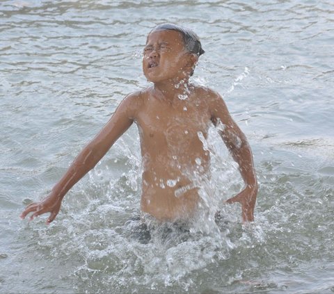 FOTO: Suhu di Bekasi Menyengat, Anak-Anak Asyik Main Air di Saluran Irigasi