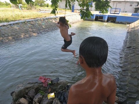 FOTO: Suhu di Bekasi Menyengat, Anak-Anak Asyik Main Air di Saluran Irigasi