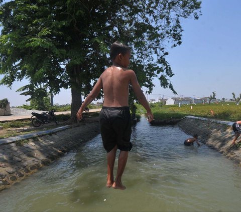 FOTO: Suhu di Bekasi Menyengat, Anak-Anak Asyik Main Air di Saluran Irigasi