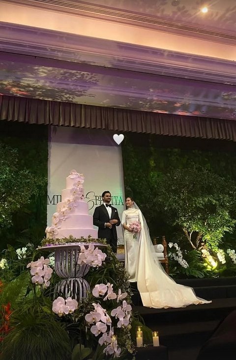 Kue pengantin berukuran raksasa disiapkan di atas panggung. Bersama sang suami, Pevita memotong kue pernikahannya dengan penuh senyum bahagia.
