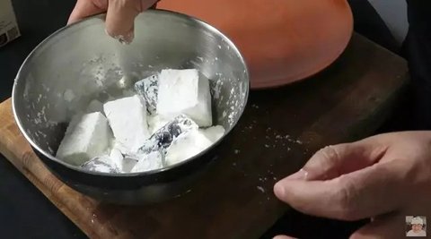 perempuan sedang menggoreng terong di dapur (ilustrasi oleh AI)