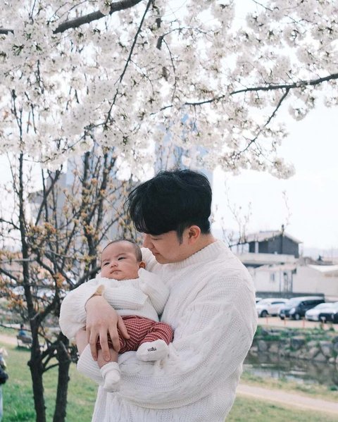 Baby Noa yang digendong bergantian oleh kedua orangtuanya begitu menggemaskan mengenakan sweater dan topi rajut yang menjaganya tetap hangat di luar ruangan.