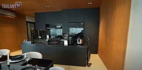 Desain dapur minimalis dengan peralatan modern. Area dapur utama dari depan. Warna dominan hitam dengan elemen kayu di dinding dan plafon membuat dapur terasa hangat namun tetap elegan.