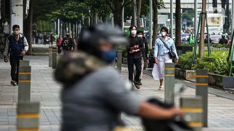 Pegawai pulang kerja berjalan di trotoar Jalan Sudirman, Jakarta, Selasa (12/5/2020). Pemerintah memberi kelonggaran bergerak bagi warga berusia di bawah 45 tahun untuk mengurangi angka pe