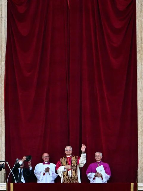 Paus Leo XIV yang baru terpilih, Robert Francis Prevost melambaikan tangan dari balkon loggia pusat utama Basilika Santo Petrus untuk pertama kalinya, setelah para kardinal mengakhiri konklaf