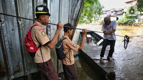 Dua orang pelajar bersiap naik perahu eretan untuk menyeberangi kali Ciliwung di kawasan Manggarai, Jakarta, Rabu (14/5/2025). (Liputan6.com/Angga Yuniar)