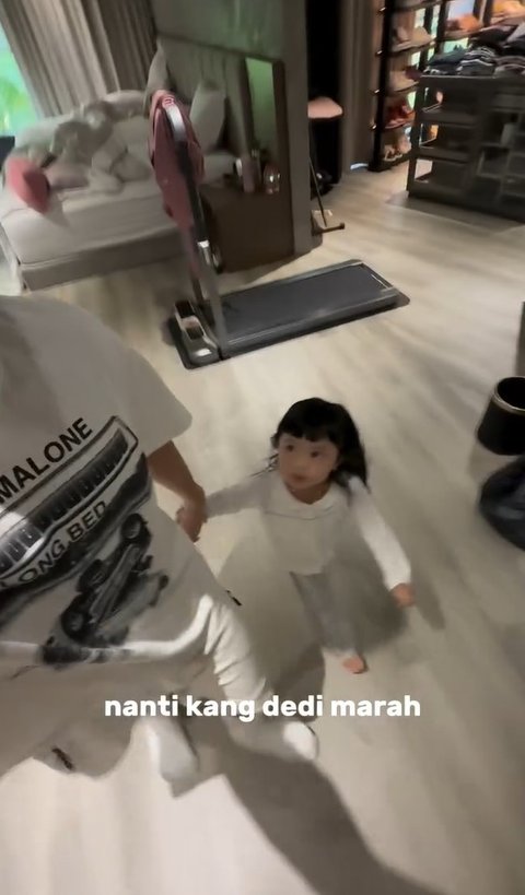 "Kang Dedi, ini ada yang nggak mau mandi Kang Dedi..." ujar Atta. Secara cepat Ameena pun langsung turun dari kasur dan menggandeng tangan papanya.
